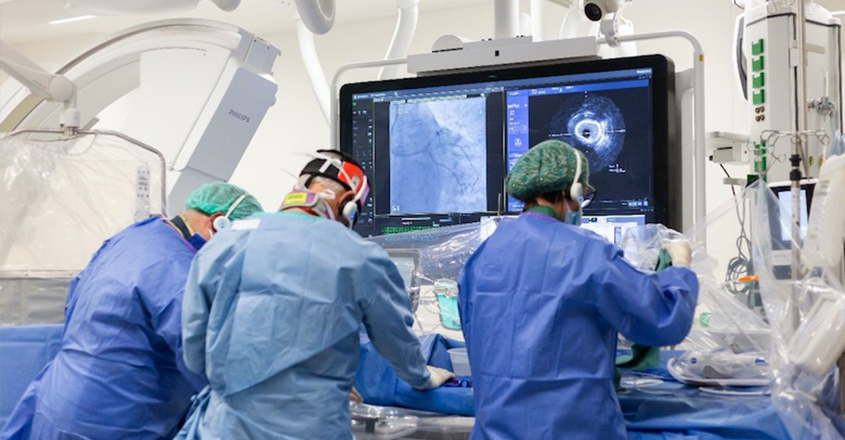Medical professionals in surgical attire conducting a procedure with advanced imaging technology in a modern operating room.